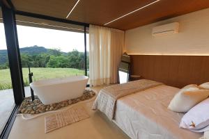 a bedroom with a large bed and a bath tub at Casa de Campo - Valle Paixão in Campo Largo