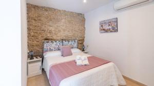 a bedroom with a bed and a brick wall at Cueva El Arrabal Setenil by Ruralidays in Setenil