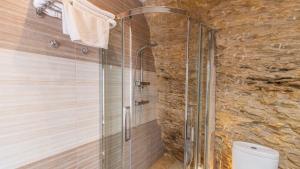 a glass shower in a bathroom with a stone wall at Cueva El Arrabal Setenil by Ruralidays in Setenil +20 photos