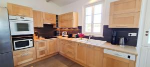 een keuken met houten kasten, een wastafel en een raam bij Dans le centre de la Couarde, superbe villa familiale in La Couarde-sur-Mer