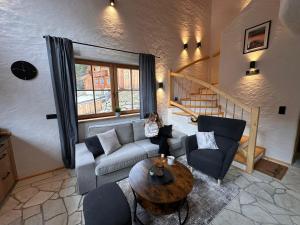 a woman sitting on a couch in a living room at Chalet am Bachl 1 in Flattach