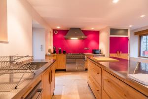 eine große Küche mit roten Wänden und Holzschränken in der Unterkunft Sejour prestige a Lannion entre ville et plages in Lannion