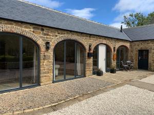 a stone house with large windows and a patio at Contemporary Luxury Barn Conversion in County Durham in Durham