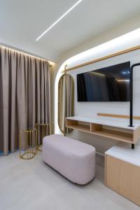 Una sala de estar con un televisor grande y un taburete. en Thea Acropolis Suites & Apartments, en Atenas