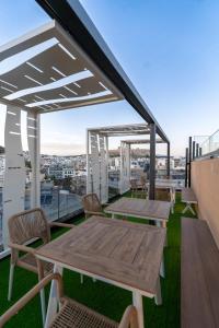 Un patio en la azotea con mesas y sillas en un edificio. en Thea Acropolis Suites & Apartments, en Atenas