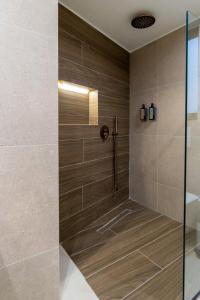 y baño con ducha y azulejos marrones. en Thea Acropolis Suites & Apartments, en Atenas 39 fotos más