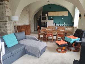 a living room with a couch and a table and a kitchen at Logis vouté les hirondelles 