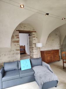 a living room with a blue couch in a stone wall at Logis vouté les hirondelles  +7 photos