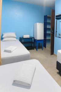 a room with two beds and a refrigerator at Alvorada Suite in Manaus