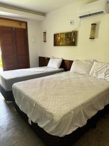 Dos camas una al lado de la otra en una habitación. en Suite com Ar e Wi Fi na Casa Full Hausi Fortim 01, en Fortim