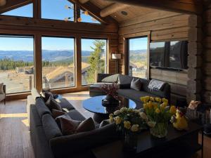 a living room with a couch and a table with flowers at Luxurious Log Cabin At Mostertoppen in Øyer