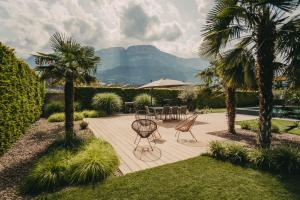 a patio with a table and chairs and palm trees at Luna apartments in Terlano