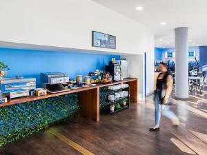 a woman walking past a counter in a store at ibis Budget Sydney Olympic Park in Sydney
