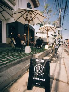 a sign on the side of a patio with umbrellas at Hi Cube Hostel in Canggu