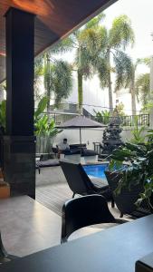 a patio with chairs and a pool and palm trees at Hi Cube Hostel in Canggu