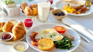 un tavolo bianco ricoperto di piatti per la colazione di فندق رهف مكة Rahaf Hotel Maka a Al Khansāk