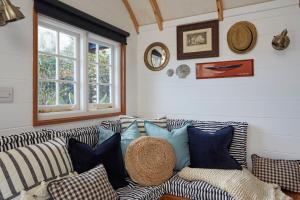 a living room with a couch with pillows at The Cabana Luxury Award Winning Tiny Home with Hot Tub and Private Garden 2 mins Walk to Ryde Beach in Ryde