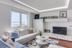 a living room with a couch and a tv at Riazor Ocean View Apartment in A Coruña