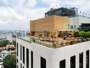 a view of a building with tables and chairs on the roof at Hotel Des Arts Saigon Mgallery Collection in Ho Chi Minh City