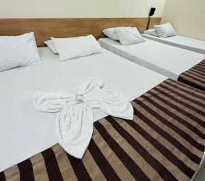 2 Betten mit weißen Handtüchern darüber in der Unterkunft Hotel Express - Leva e busca no aeroporto grátis 24 horas in Várzea Grande
