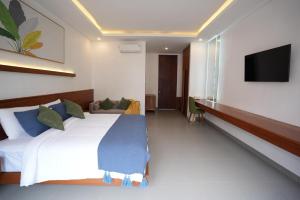 a bedroom with a large bed and a flat screen tv at Kania Rooms & Suite in Seminyak