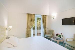 a hotel room with a white bed and a window at Grand Hotel Il Moresco in Ischia Town