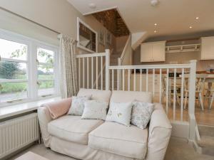 a living room with a white couch and a kitchen at Granary Cottage in Chippenham