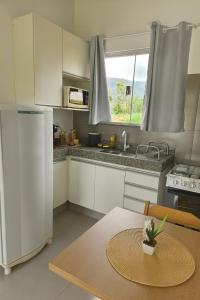 una cucina con un tavolo e un frigorifero bianco di Janela da Canastra a Capitólio Altre 6 foto