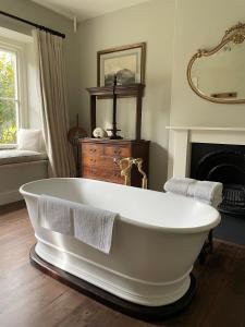 Una bañera blanca en una habitación con chimenea. en The Green, en Wingfield