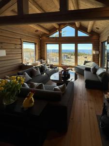 a large living room with a large couch and large windows at Luxurious Log Cabin At Mostertoppen in Øyer
