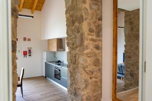 cocina y sala de estar con pared de piedra en Villae Verdasca, en Palmeira