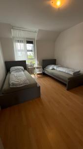 twee bedden in een kamer met houten vloeren bij BJM Comfort Apartments Oberursel in Weißkirchen