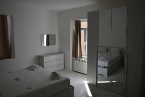 a white bedroom with a mirror and a bed at Vittoria Residence in Serravalle Scrivia