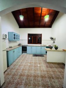 cocina grande con armarios azules y techo de madera en Hikkaduwa Magnoon Villa, en Hikkaduwa
