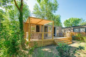a tiny house with a deck in a yard at Camping Les Pins - Bord de mer in Argelès-sur-Mer