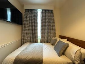 a bed in a bedroom with a large window at Hotel Cavendish - Bloomsbury in London
