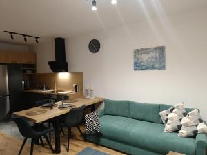 a living room with a green couch and a table at MODERN APARTAMENT Walendów Park in Walendów +11 photos