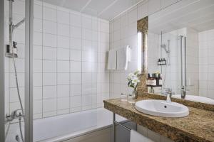 Un baño con lavabo, bañera y ducha. en NH Oberhausen, en Oberhausen