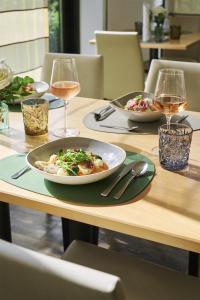 una mesa con dos platos de comida y copas de vino en NH Oberhausen, en Oberhausen