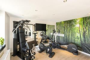 Una sala de fitness con un mural de árboles en la pared. en NH Oberhausen, en Oberhausen