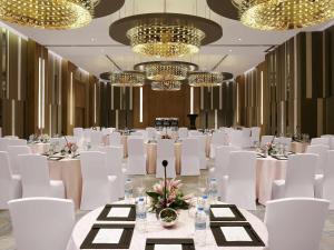 a banquet hall with white tables and chairs and chandeliers at Novotel Guwahati GS Road in Guwahati +109 photos