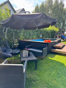 een patio met een tafel, een parasol en een zwembad bij Redwood Mielno in Mielno
