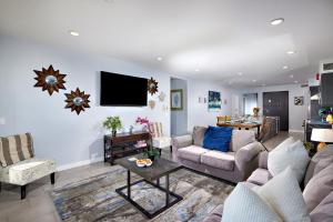 a living room with a couch and a tv on the wall at 700-104 Water Front Condo w AC in Oceanside +29 photos
