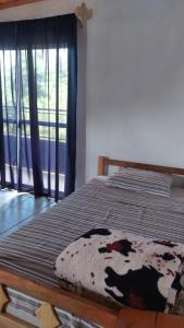 a bed in a room with a window with a blanket at Fede lll in Eldorado
