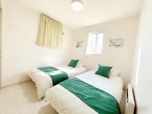 two beds in a white room with green sheets at Niseko Yotei Vista in Kutchan