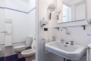 a white bathroom with a sink and a toilet at Gioia House in Milan