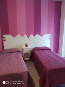 two beds in a room with purple and white walls at B&B MASSERIA U Saliére in Satriano di Lucania