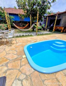 a blue swimming pool on a stone patio with a table at Casa no centro de Guapimirim, ar condicionado, piscina, churrasqueira, tranquilidade in Guapimirim