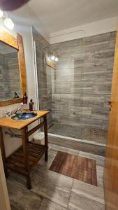 uma casa de banho com um chuveiro, uma mesa de madeira e um lavatório. em South B&B El Calafate em El Calafate mais 43 fotografias