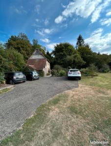 dos autos estacionados en un estacionamiento junto a un granero en Chambre privée au bord de la rivière, 